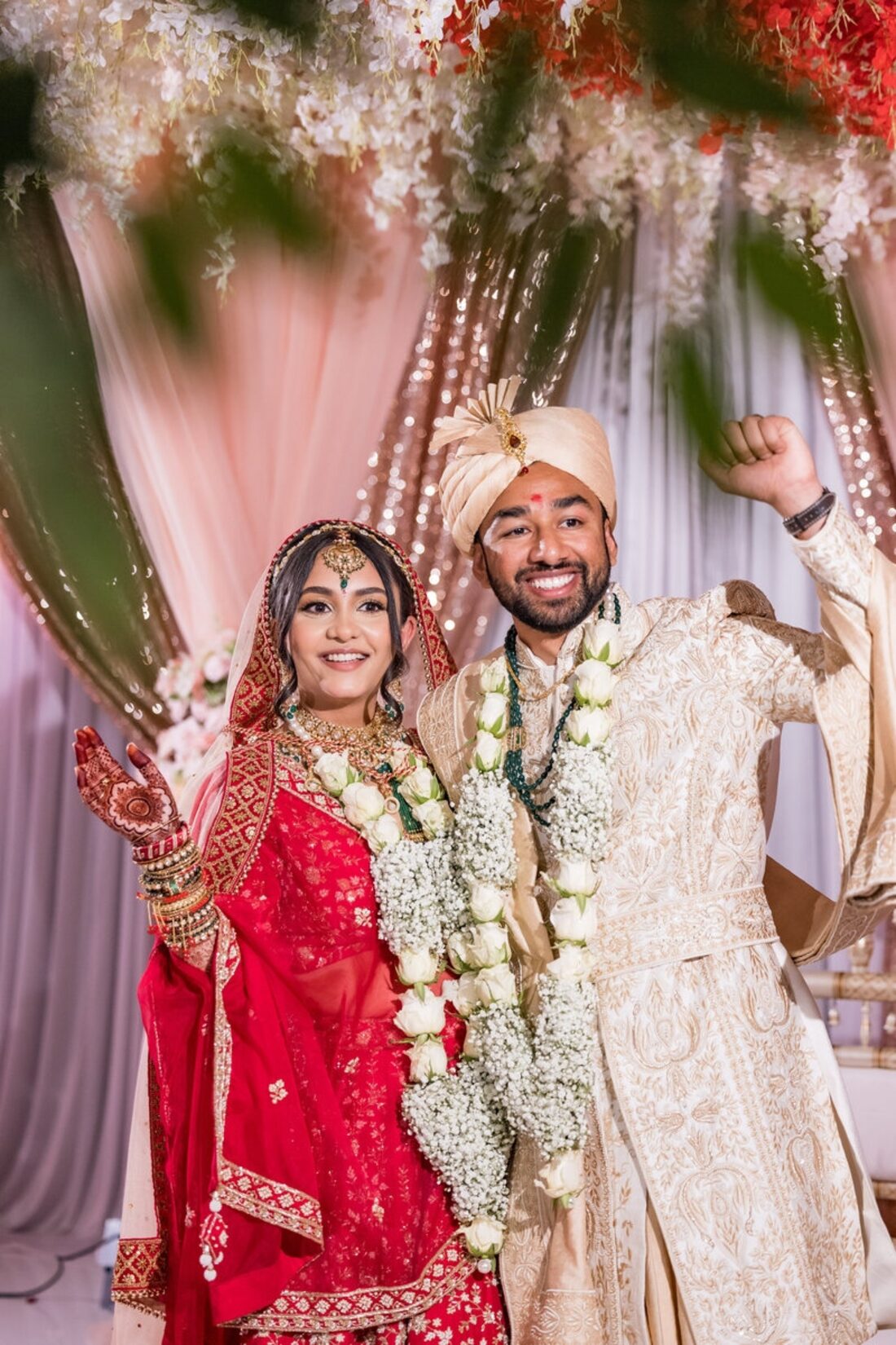 South Asian bride and groom celebrating under a floral mandap