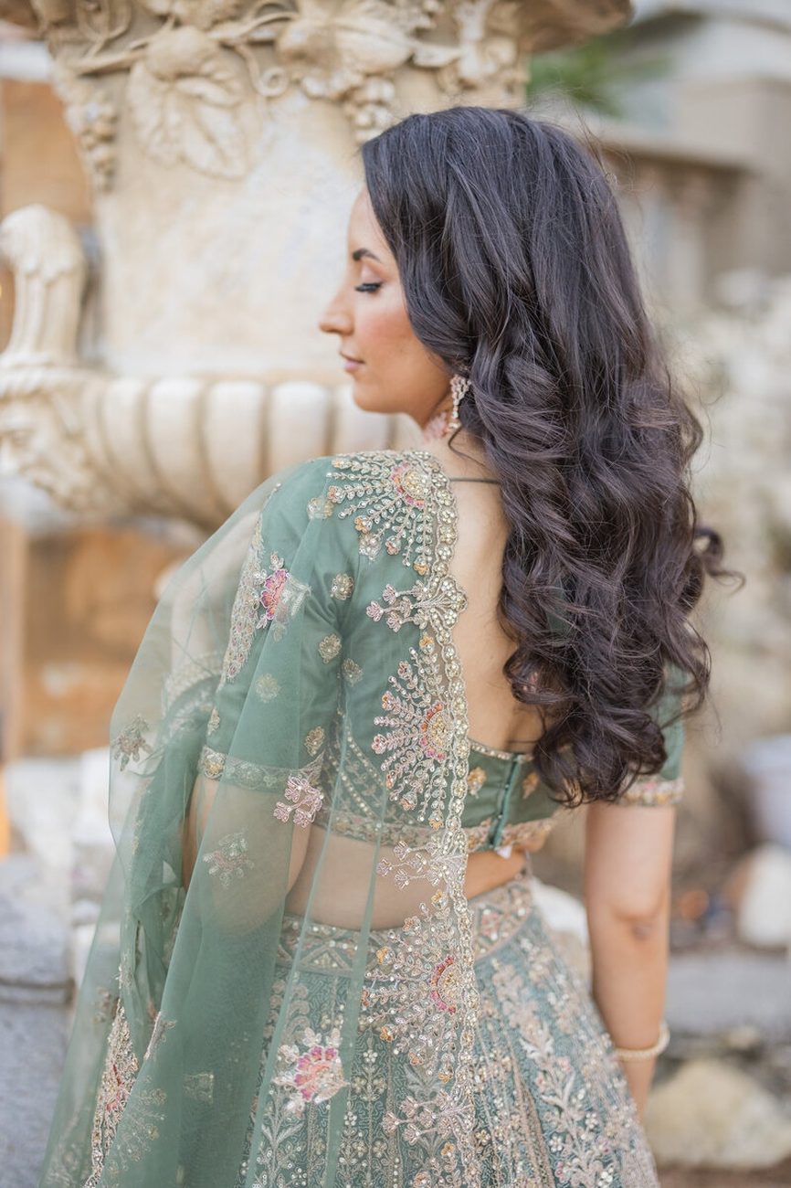 Bride in sage lehenga, back detail by ornate fountain