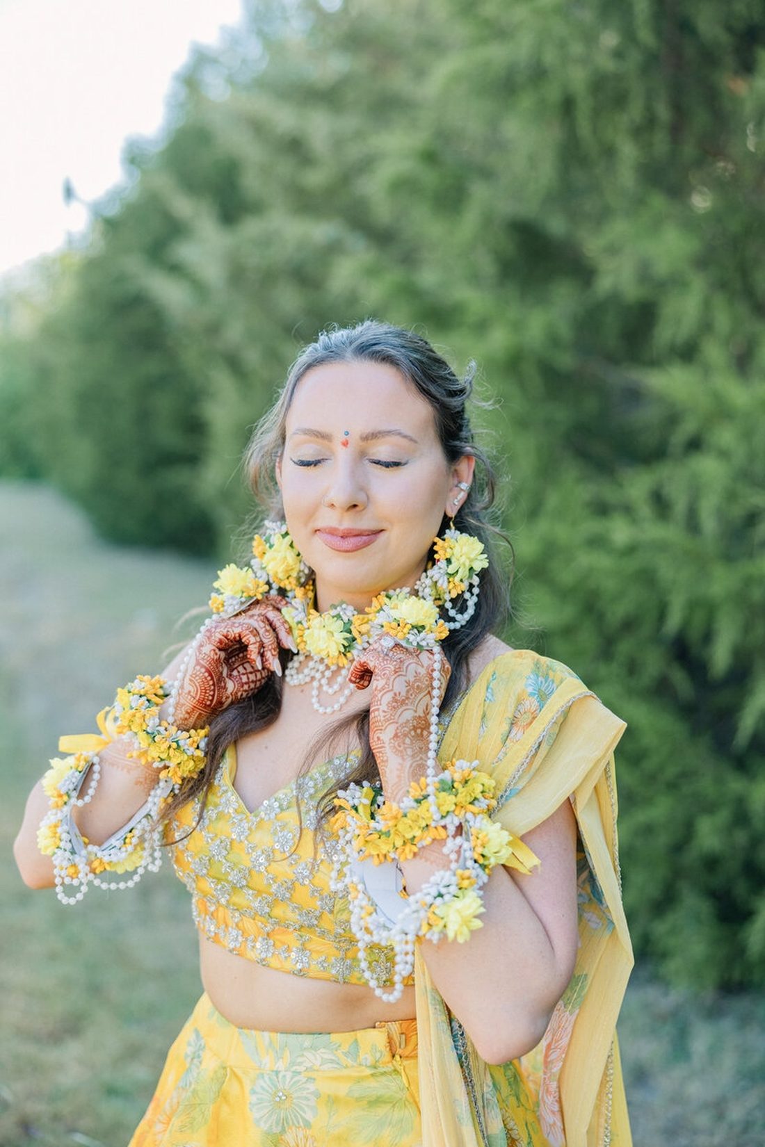Bride wearing a floral garland and yellow lehenga during her haldi celebration