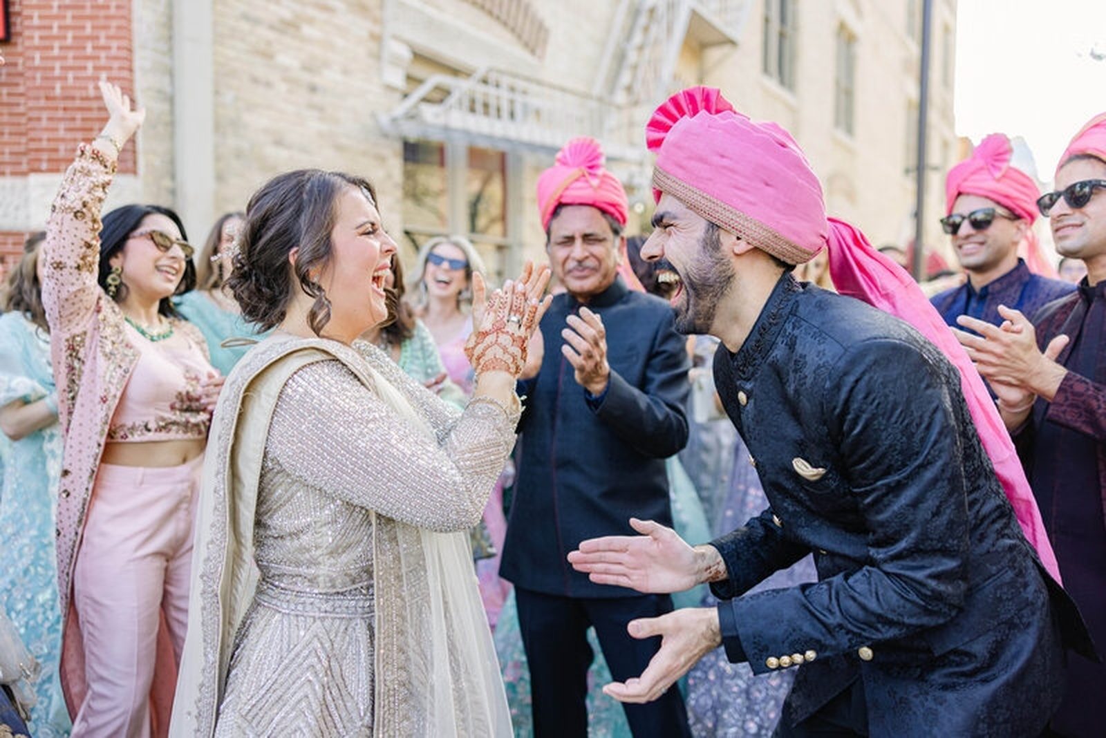 Groom in pink turban kisses bride's forehead, outdoor
