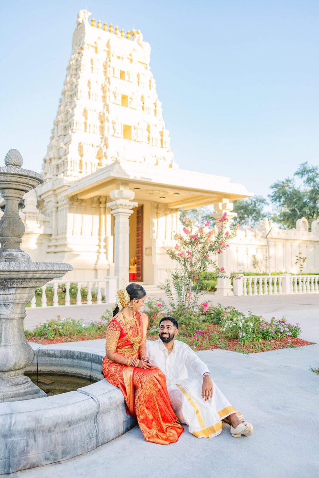 South Indian bride and groom seated together outside a temple gopuram at golden hour