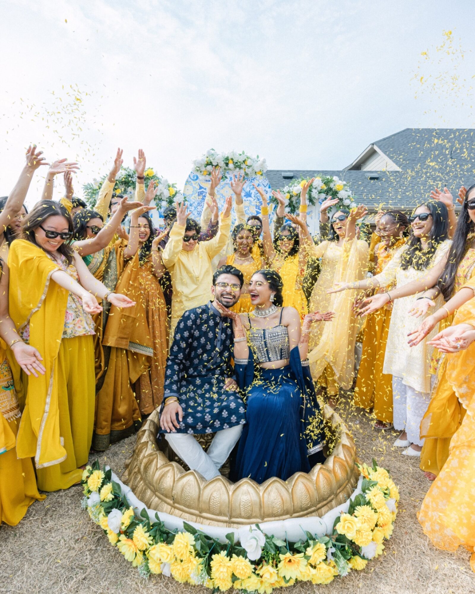 Wedding couple surrounded by family at a joyful flower-toss celebration